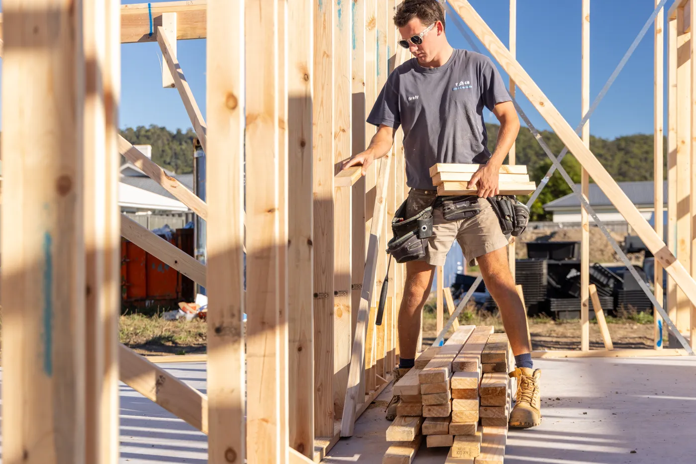 A TCB Build team member carrying timber through a new frame on site